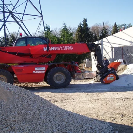 Télescopique rouge avec godet utilisé pour manipuler des matériaux en vrac
