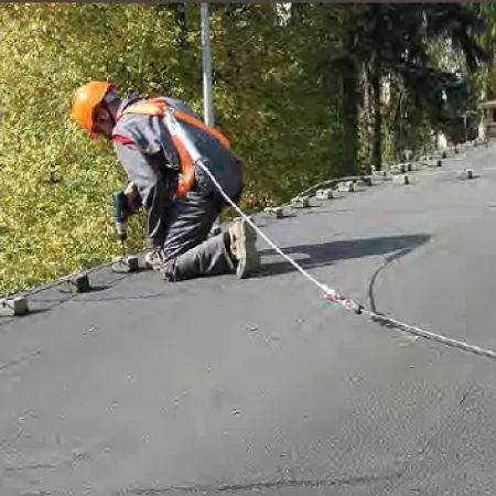 Travailleur portant un harnais de sécurité et attaché avec une longe sur un toit
